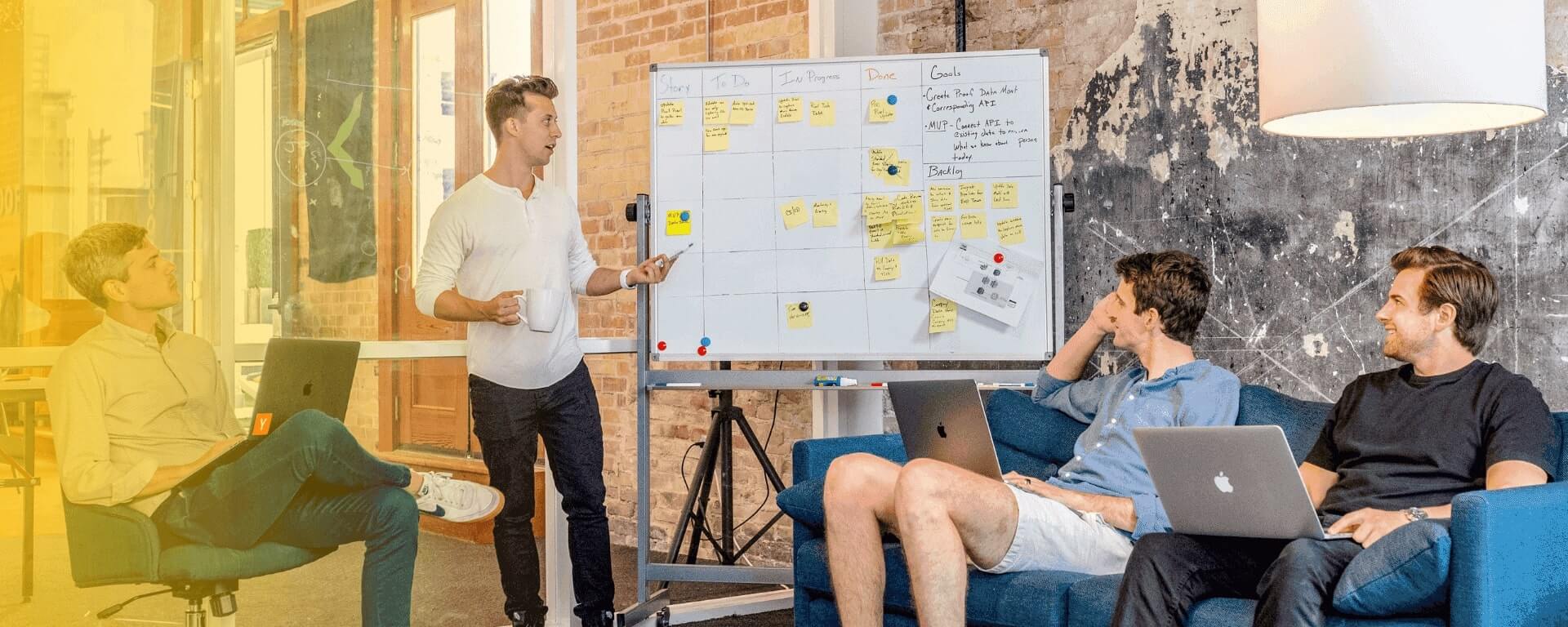 Eine Gruppe von Menschen sitzt auf Sofas in einem Büro und diskutiert miteinander.